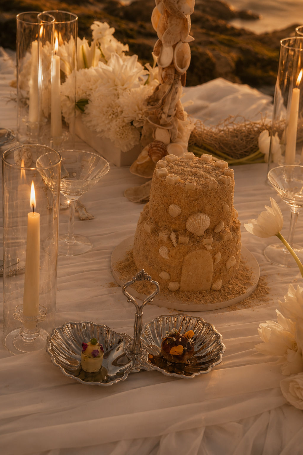 Table de réception de mariage dressée aux chandelles, fleurs et coquillages
